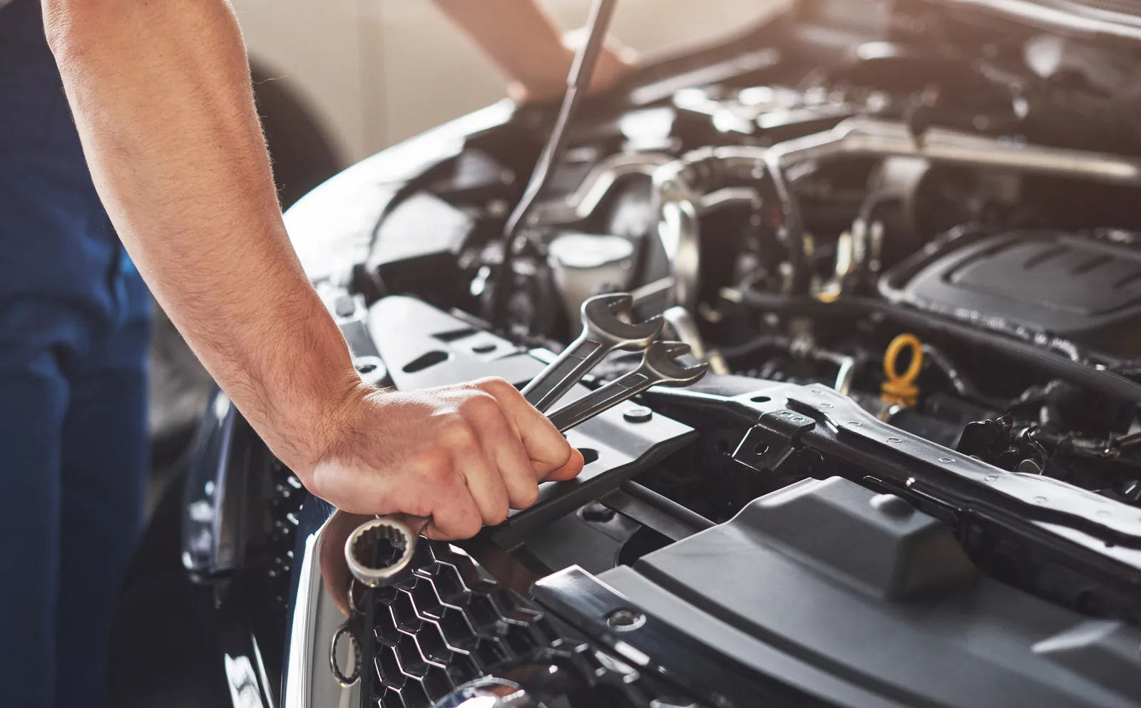 Mechanic using a socket wrench in a car engine bay