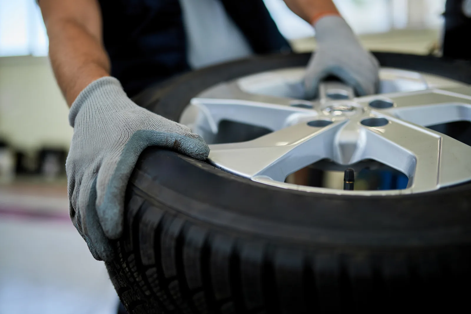 Gloved mechanic working on a tyre and alloy wheel
